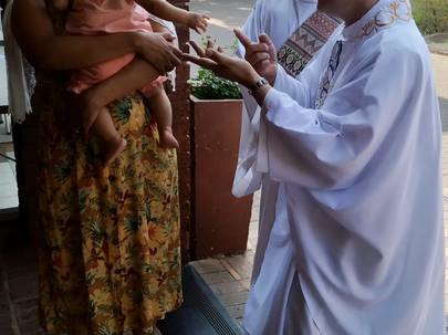 Rev. Deacon Callum Scott and Father Raul Tabaranza MCCJ greet one of our youngest parishioners before mass